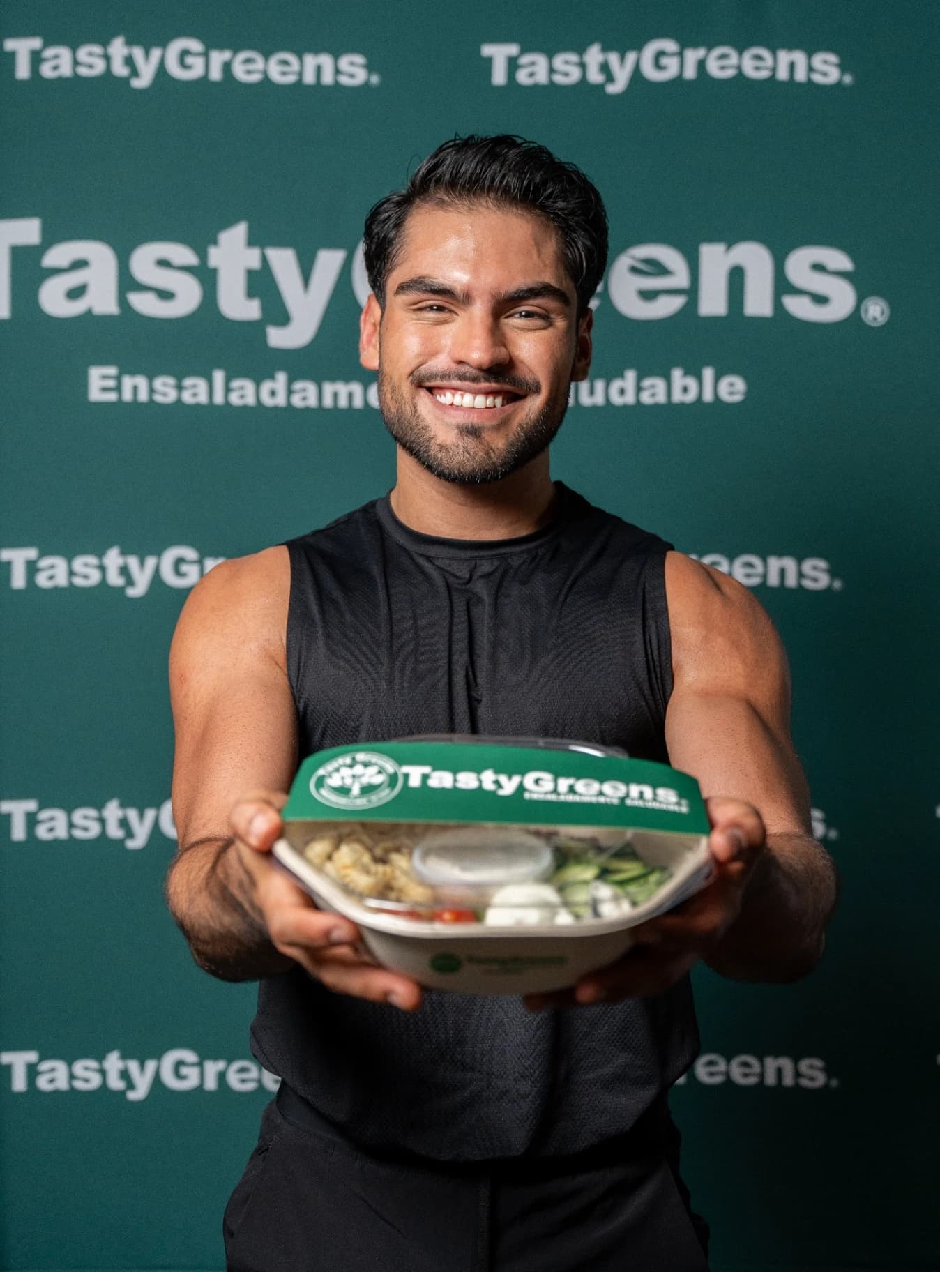 Participante de Mr Model México presentando un bowl Tasty Greens frente al backdrop de la marca
